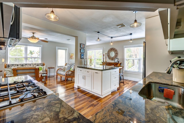 kitchen featuring sink, hanging light fixtures, dark stone countertops, gas cooktop, and white cabinets