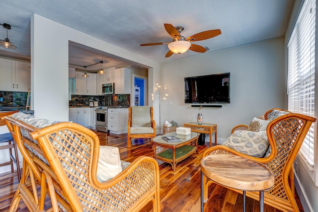 living room with ceiling fan, hardwood / wood-style floors, and a textured ceiling