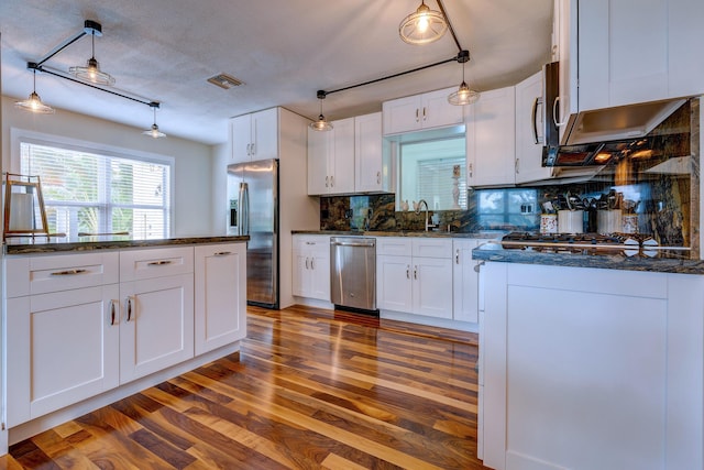 kitchen with white cabinetry, decorative light fixtures, dark hardwood / wood-style flooring, stainless steel appliances, and backsplash