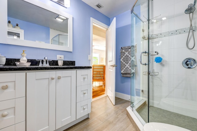 bathroom featuring vanity, an enclosed shower, and wood-type flooring