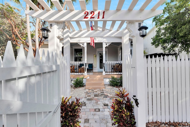 property entrance featuring covered porch and fence