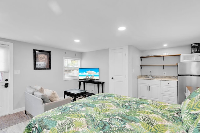 bedroom with a sink, freestanding refrigerator, recessed lighting, and wet bar