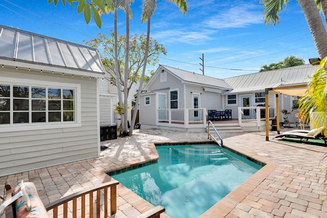 outdoor pool with a wooden deck and a patio area