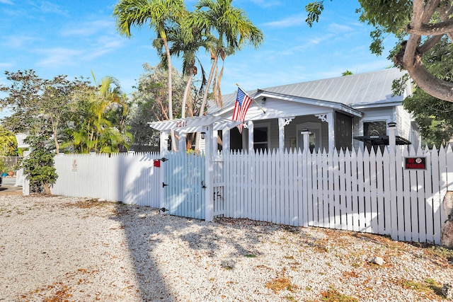 exterior space with metal roof, a fenced front yard, and a gate
