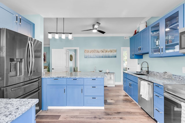 kitchen featuring stainless steel appliances, blue cabinetry, ceiling fan, and a sink