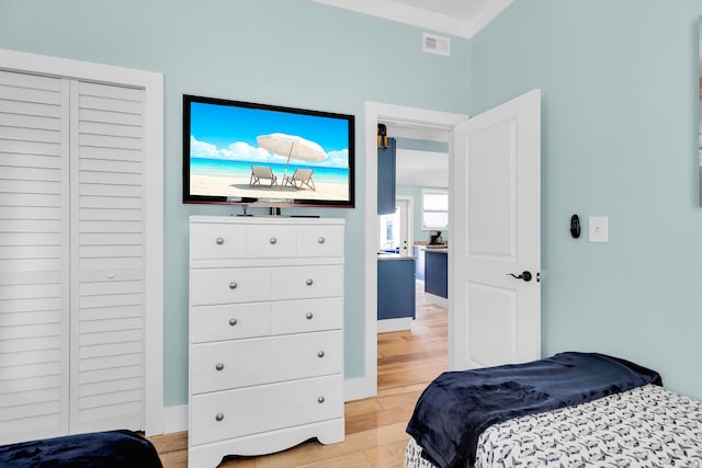 bedroom with visible vents, light wood finished floors, and baseboards