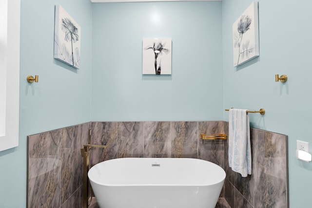 full bath with a freestanding tub, tile walls, and a wainscoted wall