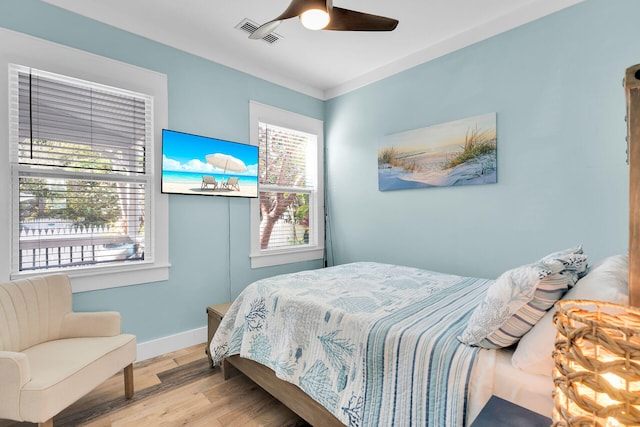 bedroom with visible vents, baseboards, wood finished floors, and multiple windows