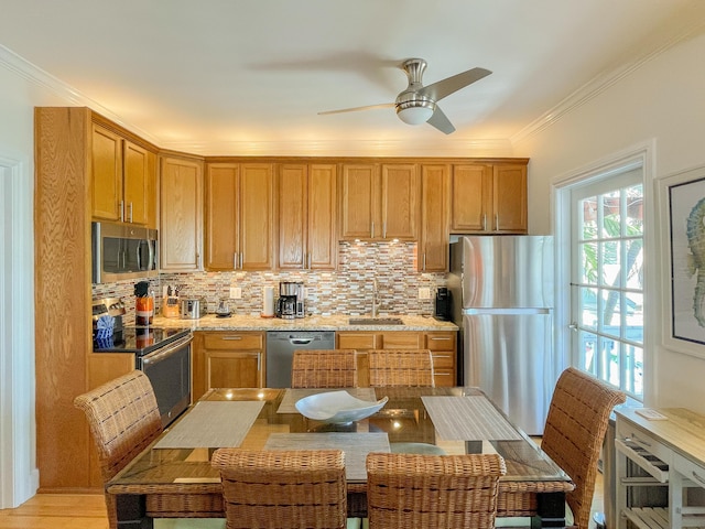 kitchen with sink, light stone counters, ornamental molding, appliances with stainless steel finishes, and decorative backsplash