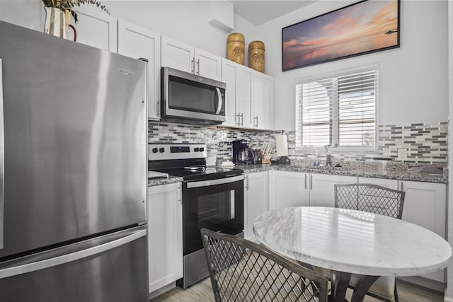 kitchen featuring tasteful backsplash, white cabinetry, sink, dark stone countertops, and stainless steel appliances