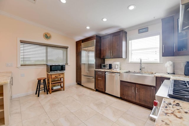 kitchen with sink, dark brown cabinets, stainless steel appliances, and light stone countertops