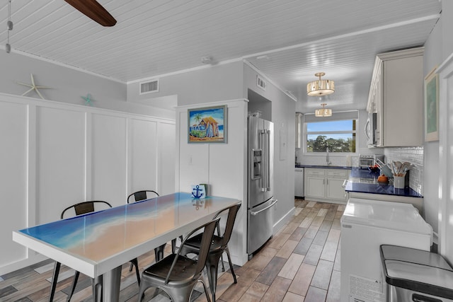 kitchen with sink, appliances with stainless steel finishes, hanging light fixtures, backsplash, and washer / dryer