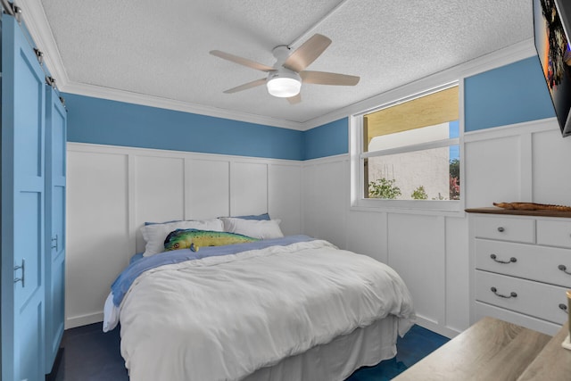 bedroom featuring ceiling fan, ornamental molding, a barn door, and a textured ceiling