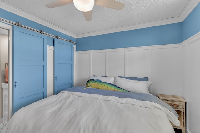 bedroom featuring ornamental molding, a barn door, and a textured ceiling