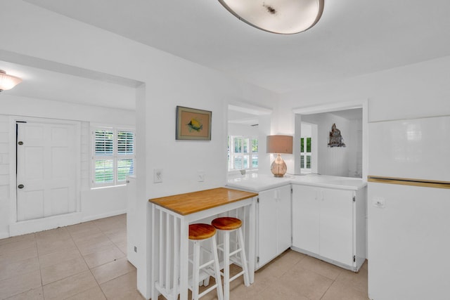 22841 Buccaneer Ln, Cudjoe, FL 33042 - kitchen with freestanding refrigerator, light tile patterned floors, light countertops, and white cabinetry