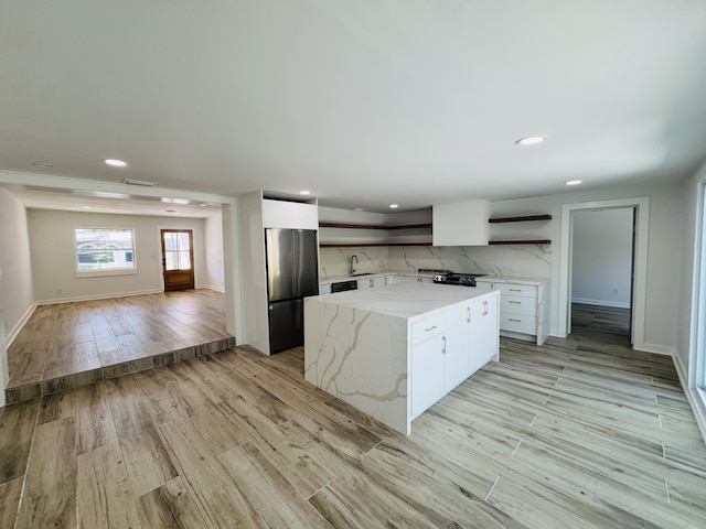 1708 Duncan St, Key West, FL 33040 - kitchen with open shelves, stainless steel fridge, a center island, white cabinetry, and light wood-style flooring