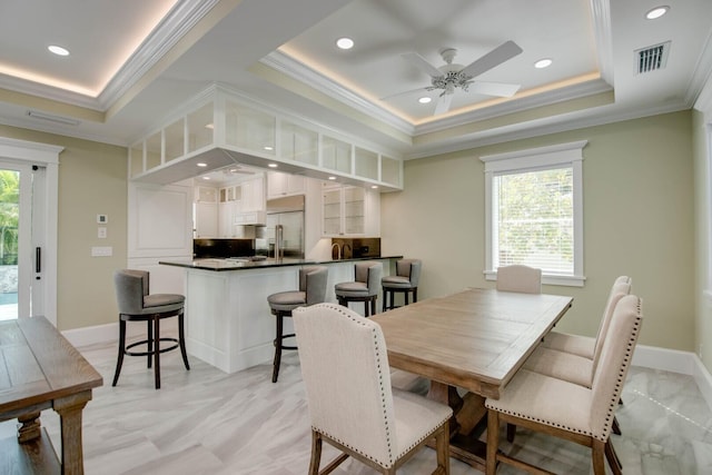 dining space with a tray ceiling, ornamental molding, and ceiling fan