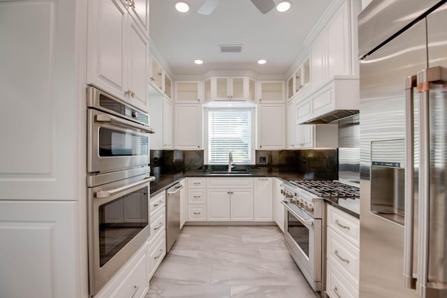 kitchen featuring high end appliances, white cabinetry, sink, and decorative backsplash