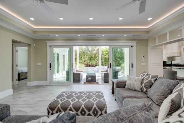 living room with a tray ceiling, ornamental molding, and ceiling fan