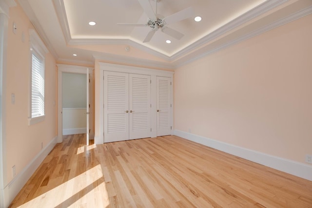 unfurnished bedroom with lofted ceiling, ornamental molding, light hardwood / wood-style floors, and a raised ceiling