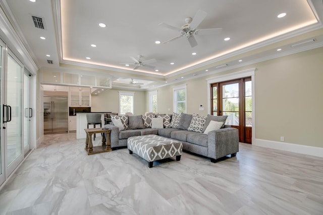 living room featuring ornamental molding, ceiling fan, and a tray ceiling