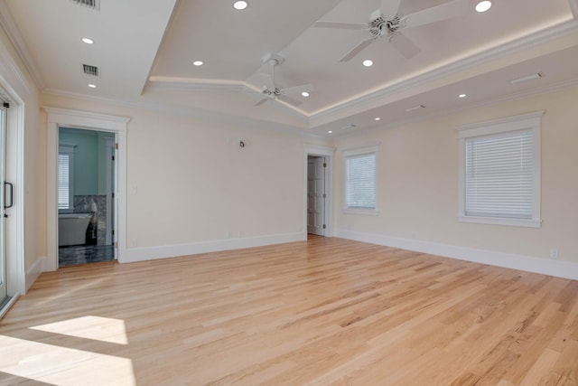 empty room with crown molding, light hardwood / wood-style floors, and a raised ceiling