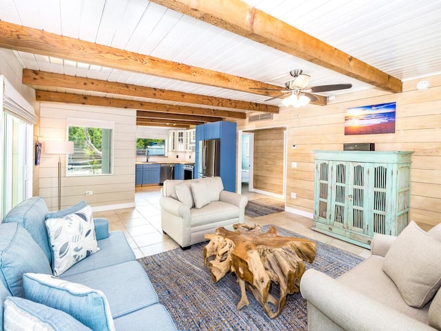 living room featuring sink, wood walls, light tile patterned floors, ceiling fan, and beam ceiling