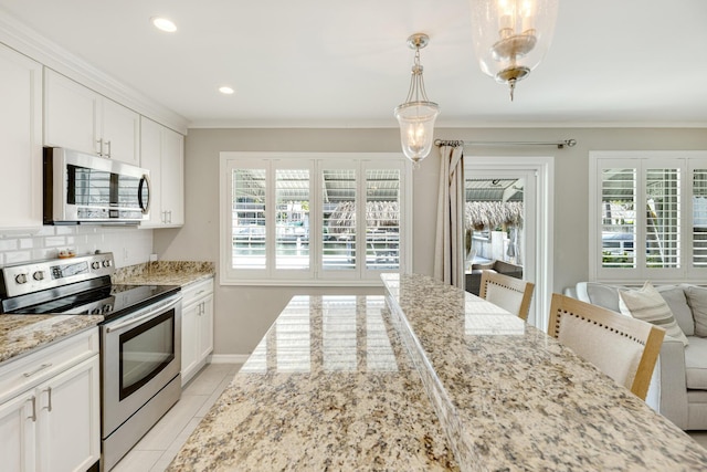 240 S Coconut Palm Blvd, Tavernier, FL 33070 - kitchen with stainless steel appliances, light stone countertops, light tile patterned floors, white cabinets, and crown molding