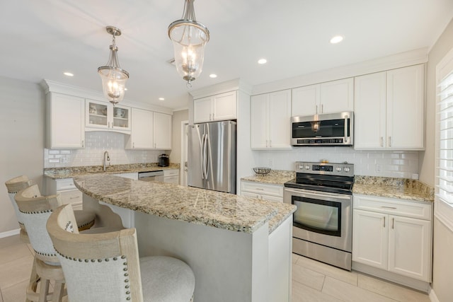 240 S Coconut Palm Blvd, Tavernier, FL 33070 - kitchen with appliances with stainless steel finishes, tasteful backsplash, light tile patterned floors, white cabinetry, and a kitchen island