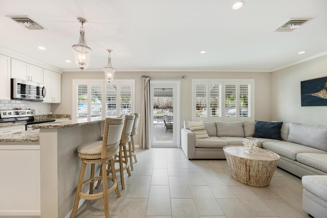 240 S Coconut Palm Blvd, Tavernier, FL 33070 - kitchen featuring appliances with stainless steel finishes, open floor plan, light stone countertops, a kitchen breakfast bar, and ornamental molding