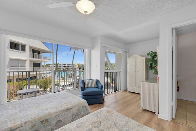 95 Coco Plum Dr Unit 2D, Marathon, FL 33050 - bedroom featuring access to outside, a textured ceiling, a water view, wood finished floors, and a ceiling fan