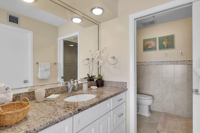 95 Coco Plum Dr Unit 2D, Marathon, FL 33050 - full bath featuring toilet, tile patterned floors, vanity, tile walls, and a wainscoted wall