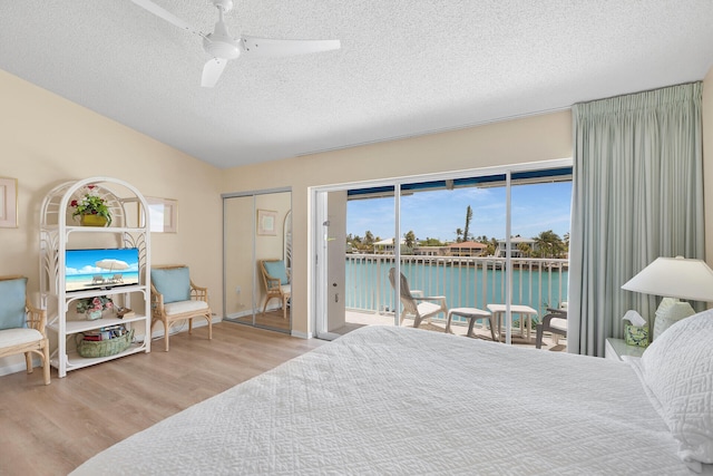 95 Coco Plum Dr Unit 2D, Marathon, FL 33050 - bedroom with access to exterior, wood finished floors, a textured ceiling, vaulted ceiling, and a water view