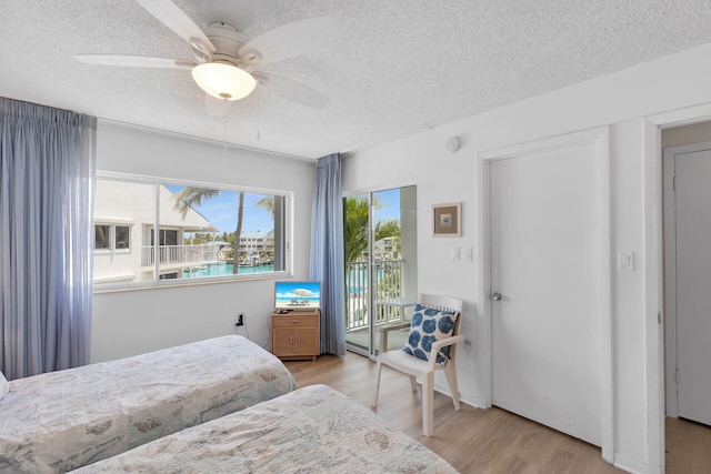 95 Coco Plum Dr Unit 2D, Marathon, FL 33050 - bedroom with access to exterior, a textured ceiling, wood finished floors, and ceiling fan