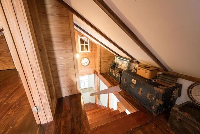 stairs featuring vaulted ceiling, wooden walls, and hardwood / wood-style floors