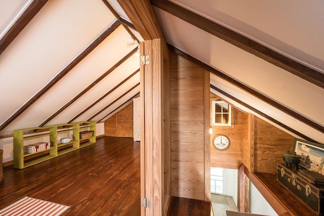 additional living space with lofted ceiling with beams, dark wood-type flooring, and wood walls