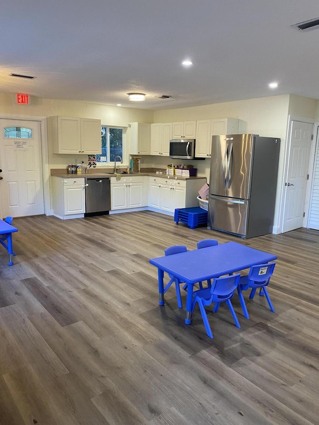 kitchen with white cabinets, visible vents, stainless steel appliances, and wood finished floors