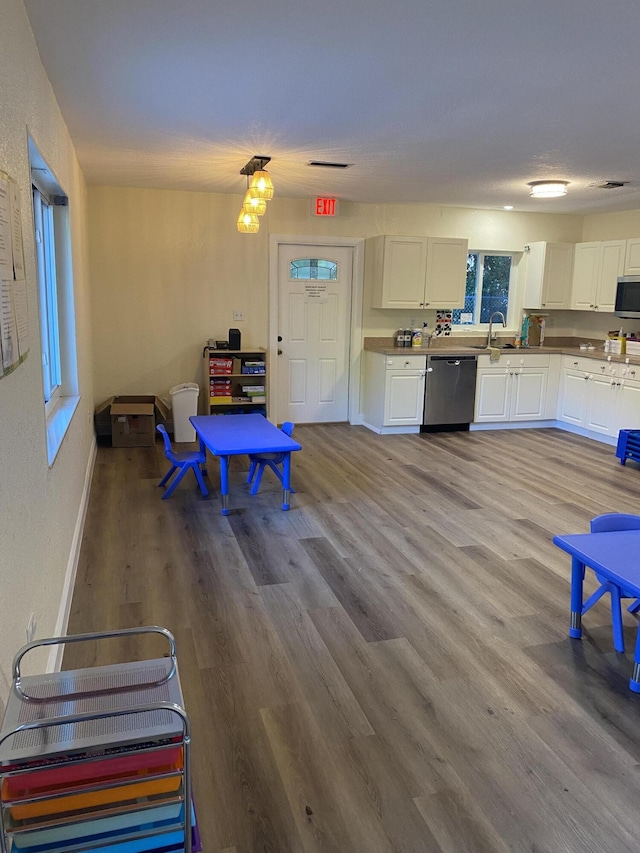 interior space with appliances with stainless steel finishes, white cabinets, and wood finished floors