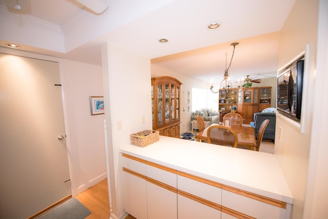 kitchen featuring white cabinetry, hanging light fixtures, a notable chandelier, kitchen peninsula, and light hardwood / wood-style flooring