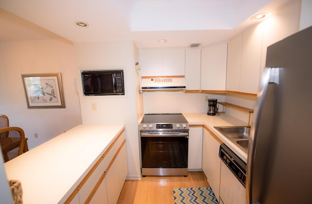 kitchen featuring stainless steel appliances, sink, light hardwood / wood-style flooring, and white cabinets