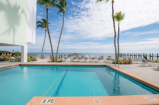 view of pool featuring a water view and a patio area