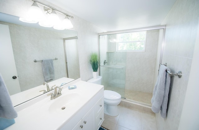 bathroom with toilet, a shower with shower door, tile walls, vanity, and tile patterned flooring