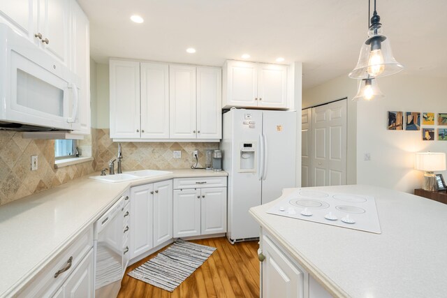 kitchen with pendant lighting, white appliances, sink, and white cabinets