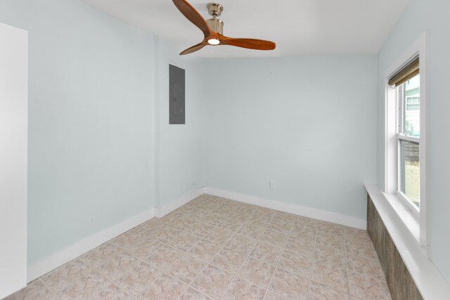 empty room with light tile patterned flooring, ceiling fan, and electric panel