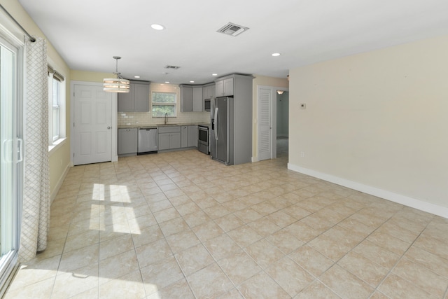 kitchen featuring gray cabinets, pendant lighting, sink, backsplash, and stainless steel appliances