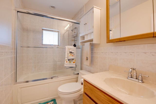 full bathroom featuring tile walls, vanity, combined bath / shower with glass door, and toilet