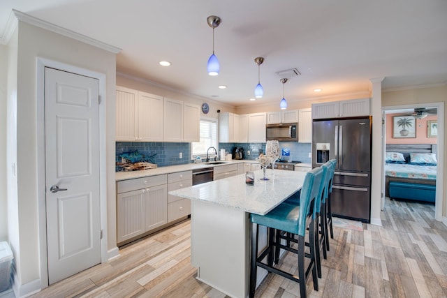 kitchen featuring a kitchen island, a breakfast bar, sink, hanging light fixtures, and stainless steel appliances