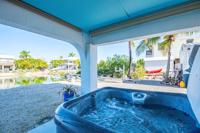 view of patio / terrace with a water view and a hot tub