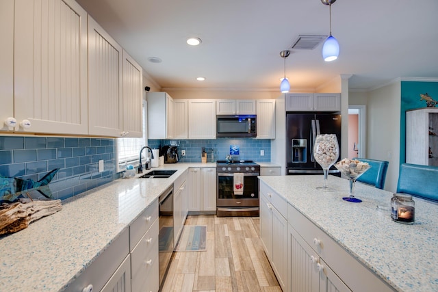 kitchen featuring sink, hanging light fixtures, ornamental molding, light stone countertops, and black appliances