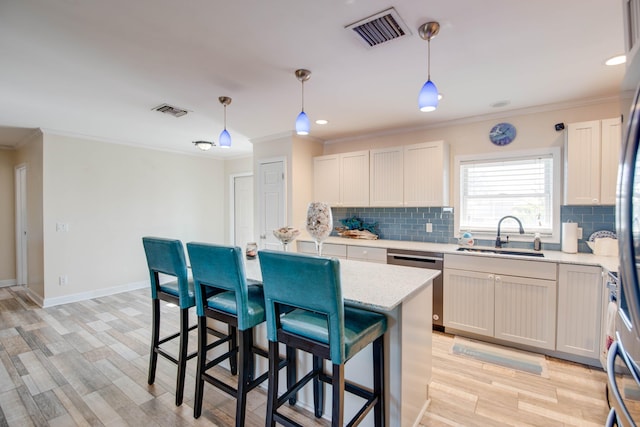 kitchen with pendant lighting, sink, ornamental molding, and stainless steel dishwasher